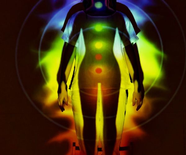 Silhouette of a woman meditating with a glowing energy aura.